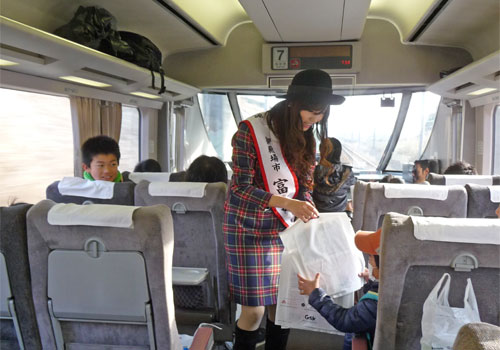 富士山トレイン371の車内でパンフレットを配る富士娘